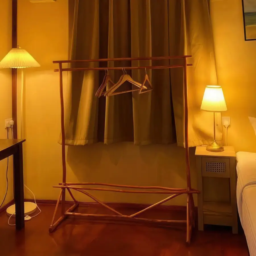 A charming chalet bedroom at Coco Seaweed Resort near Pulau Bum Bum featuring a large bed, traditional style wooden table, sleek timber floors, AC, and an open glass door leading to the deck.